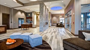A spacious lobby with a central stone pillar, a reception desk, and a seating area with ottomans and a coffee table. - Homewood Suites by Hilton Nashville Franklin Cool Springs (Franklin)