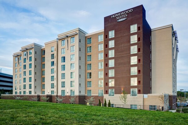 Ein mehrgeschossiges Hotel mit einem gut sichtbaren Schild "Homewood Suites", das ein modernes architektonisches Design mit Ziegel- und Beige-Fassaden sowie ein Flachdach aufweist.