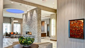 A modern lobby with a stone accent wall, a seating area with a sofa and a coffee table, and a framed artwork on the wall. - Homewood Suites by Hilton Nashville Franklin Cool Springs (Franklin)