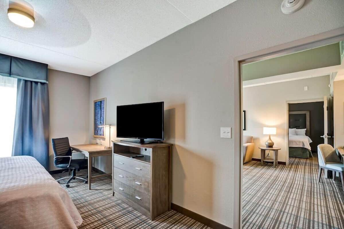 A hotel room with a bed, desk, chair, television, and a mirror.