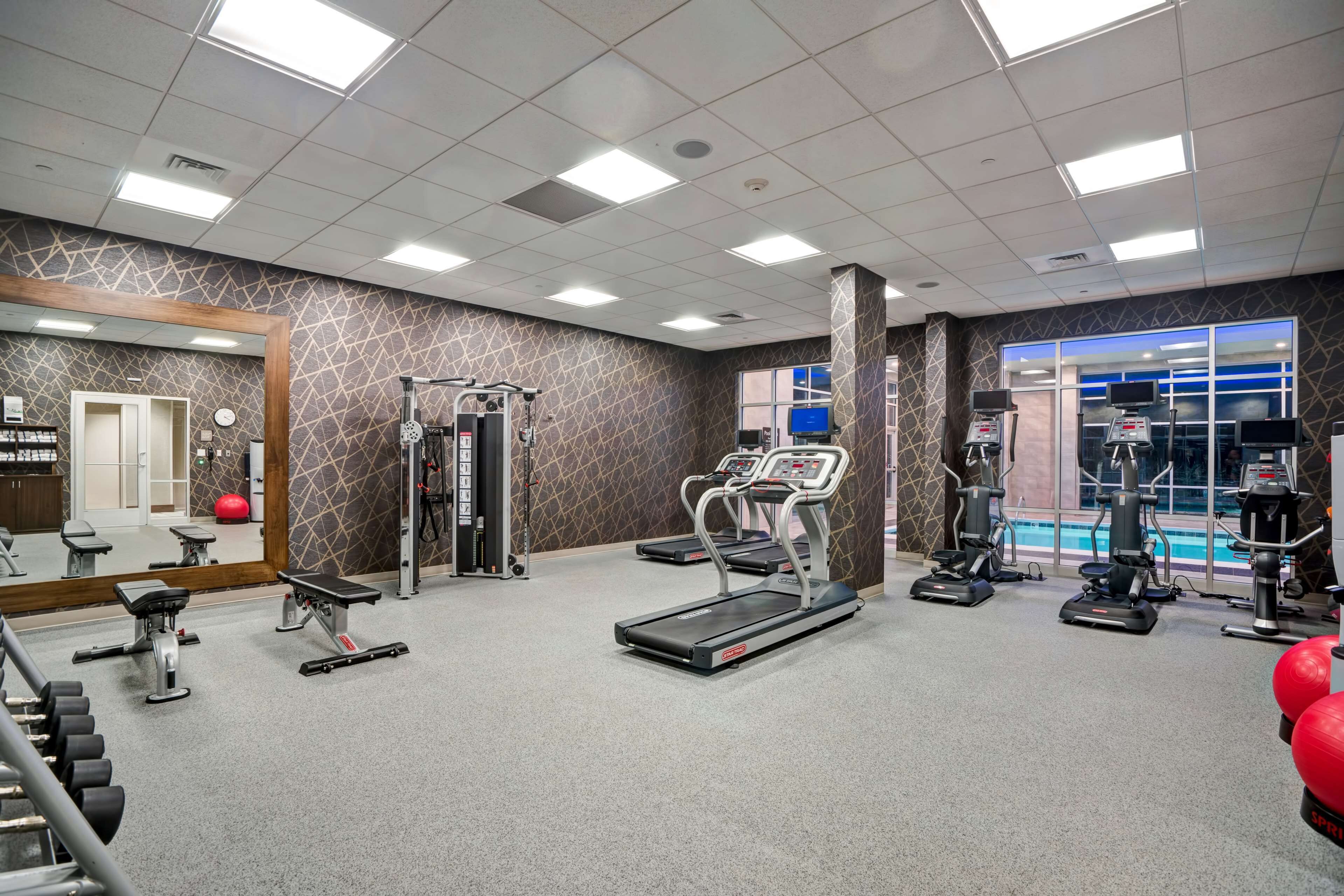 A gym with treadmills, weight machines, and a mirrored wall.