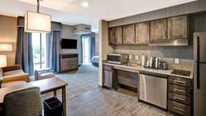 A modern hotel room with a kitchenette, a seating area with a sofa and chairs, and a large window offering a view. - Homewood Suites by Hilton Nashville Franklin Cool Springs (Franklin)