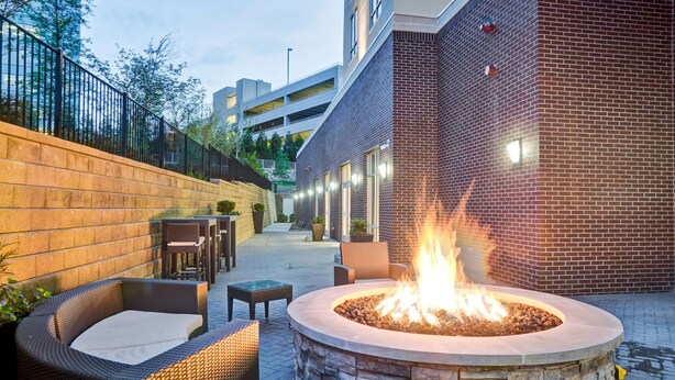 An outdoor patio area with a fire pit, wicker furniture, and a brick wall. - Homewood Suites by Hilton Nashville Franklin Cool Springs (Franklin)