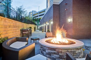 An outdoor patio area with a fire pit, wicker furniture, and a brick wall. - Homewood Suites by Hilton Nashville Franklin Cool Springs (Franklin)
