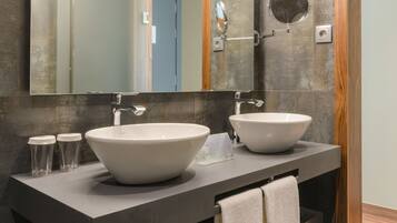 A modern bathroom with two large white sinks, a mirror, and a towel rack.