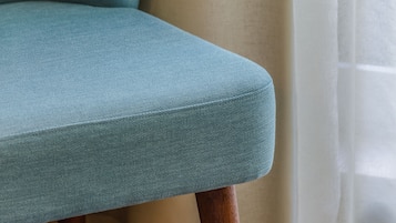 Primer plano de una silla tapizada en color verde azulado con patas de madera.