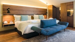 A modern bedroom with a large bed, a blue sofa, and a wooden headboard. - Hotel Vincci Liberdade (Lisbon)
