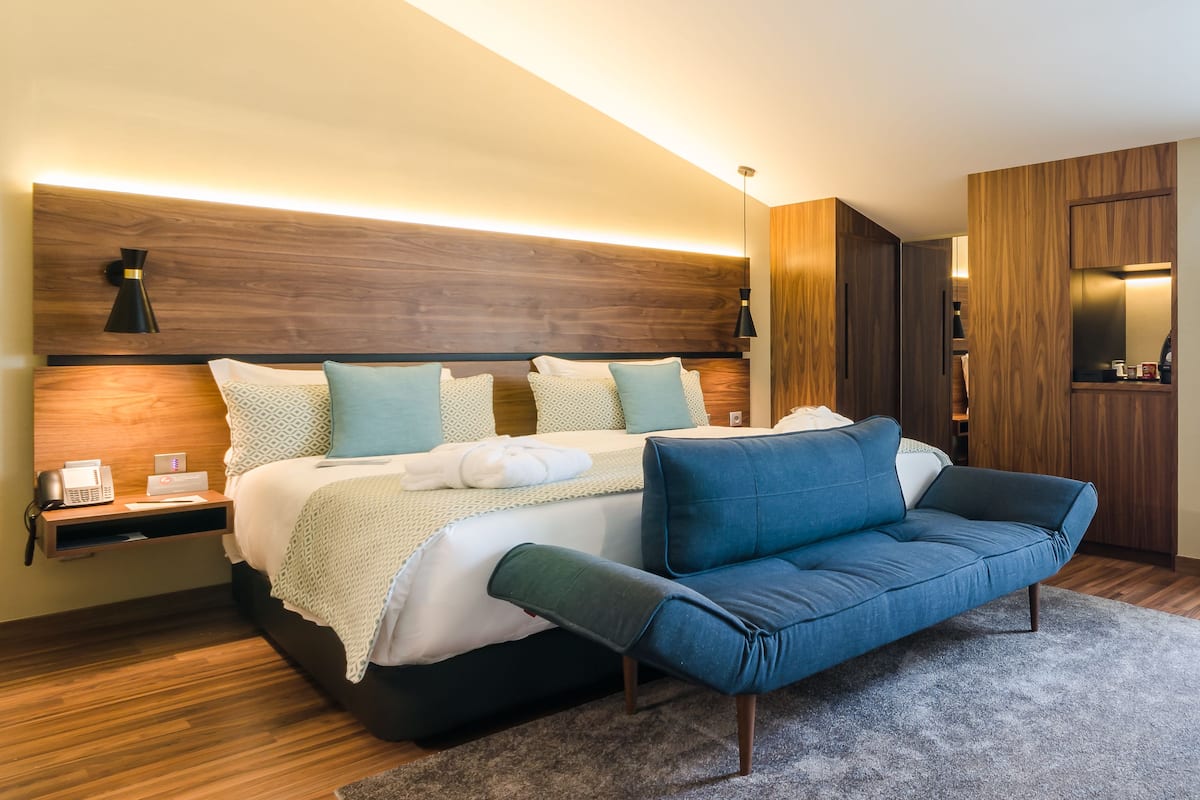 A modern bedroom with a large bed, a blue sofa, and a wooden headboard.