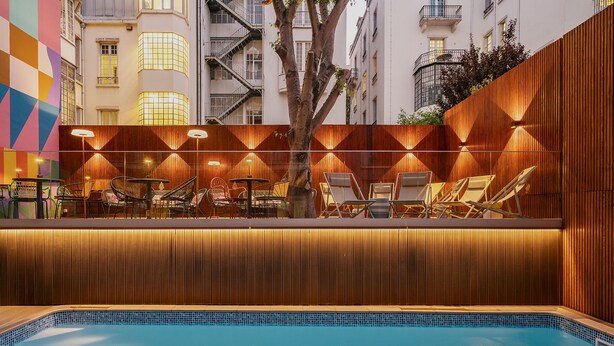 A poolside lounge with wooden paneling and lounge chairs, surrounded by a tiled pool. - Hotel Vincci Liberdade (Lisbon)