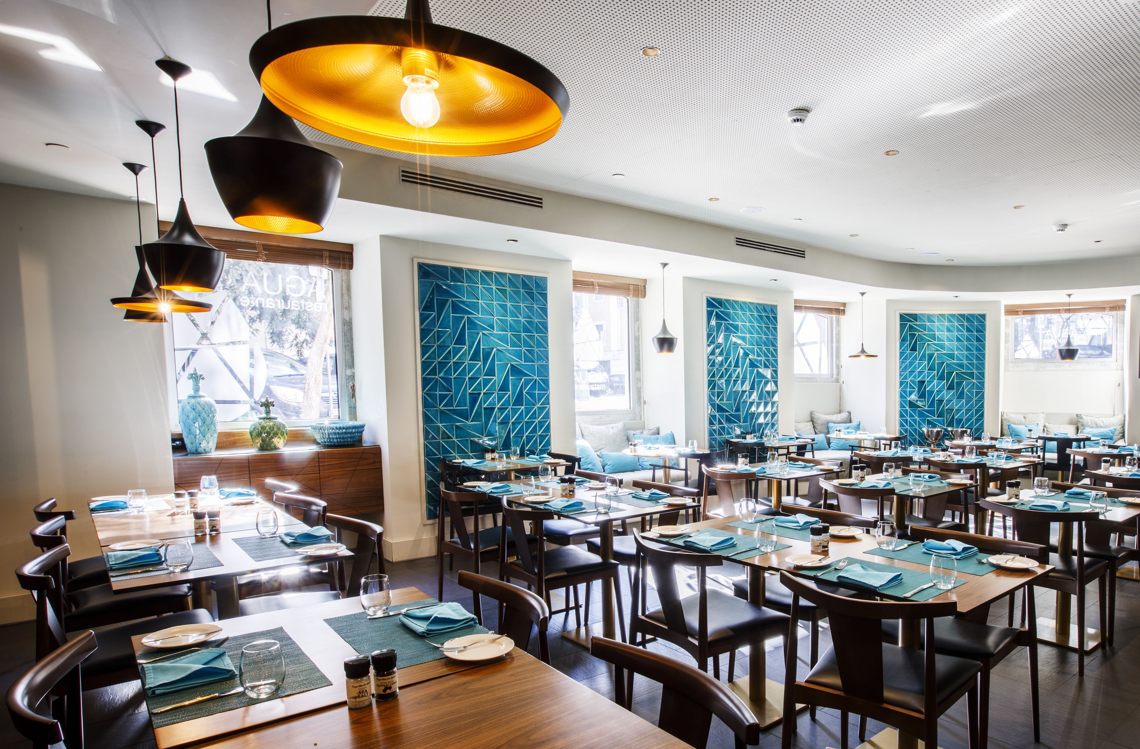 Un restaurante con varias mesas, sillas e iluminación colgante.