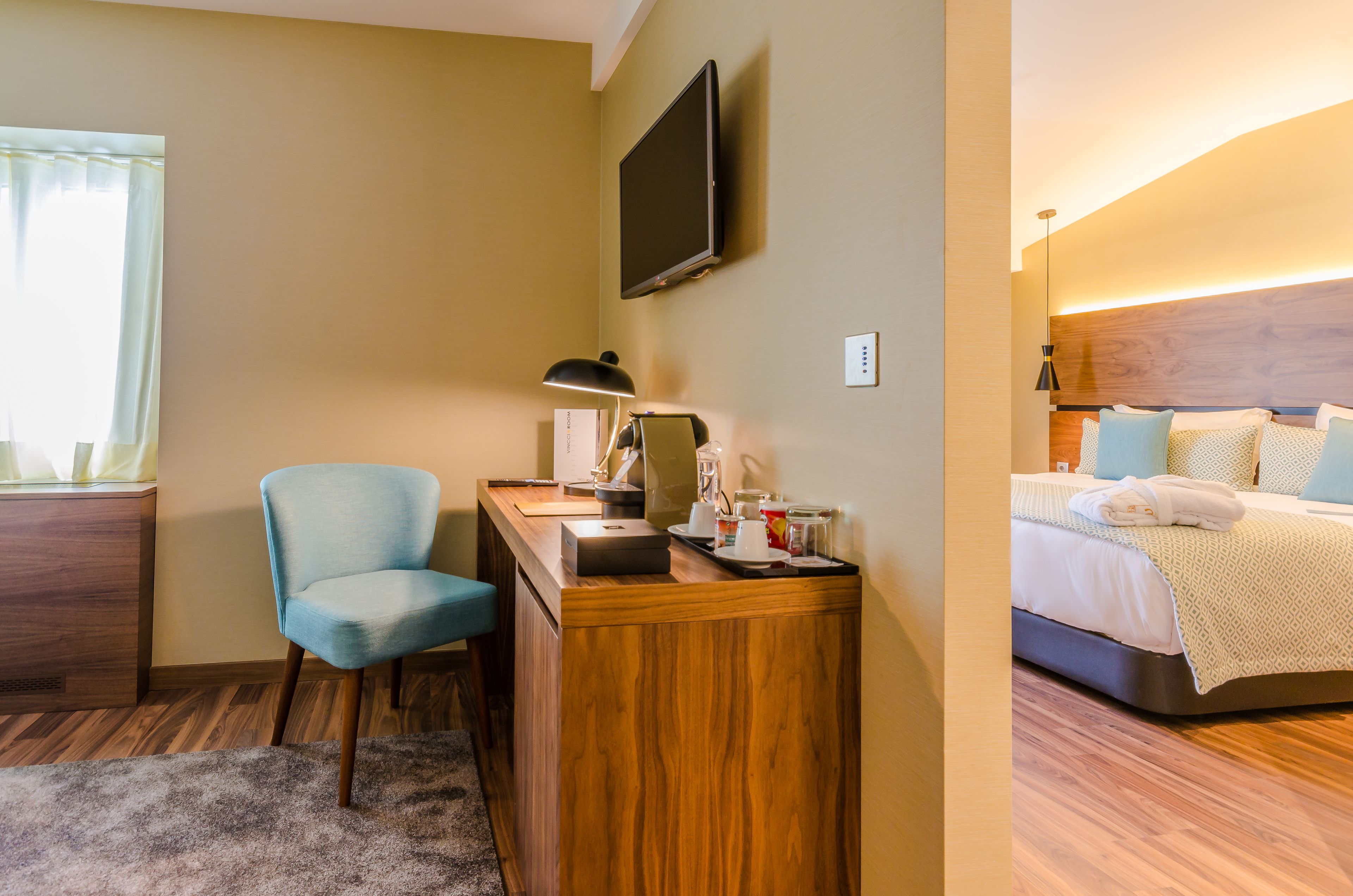 Habitación de hotel con escritorio, silla, televisor de pantalla plana y cama con cabecera.