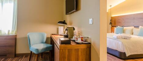 Habitación de hotel con escritorio, silla, televisor de pantalla plana y cama con cabecera.