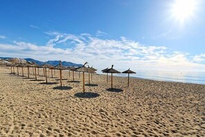A beach with rows of thatched umbrellas and a clear sky. - R2 Cala Millor (Son Servera)
