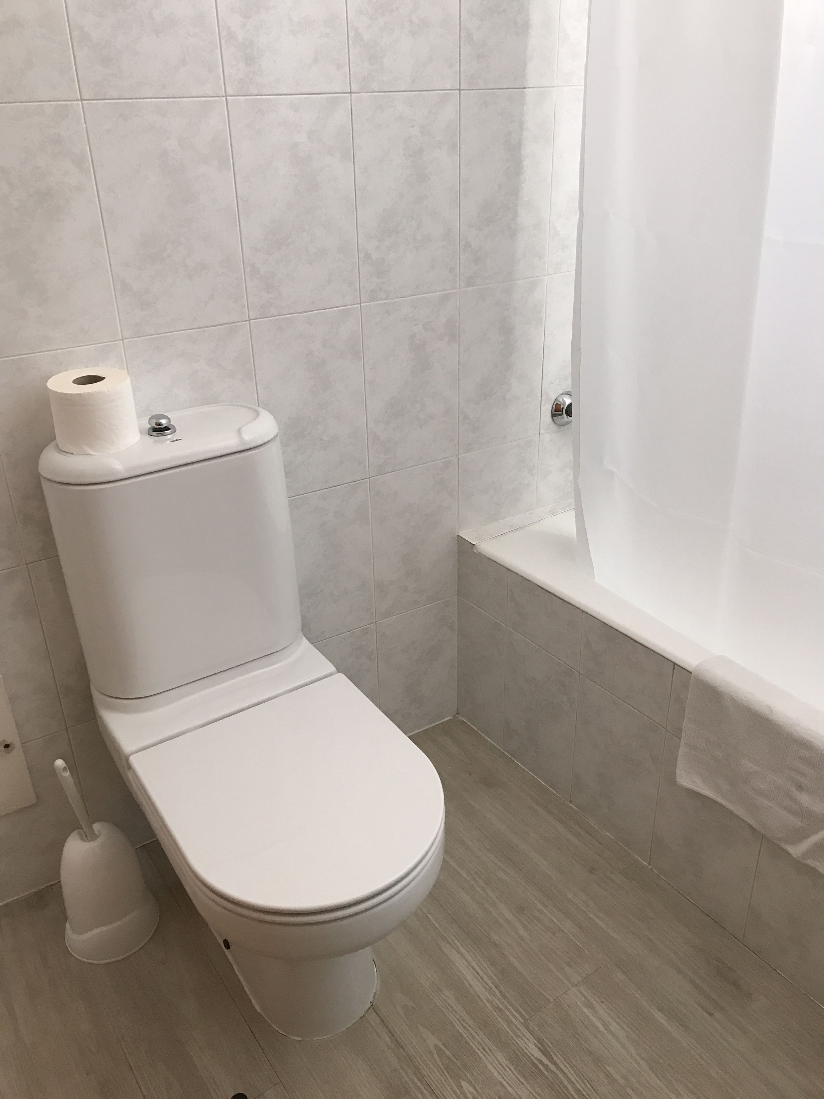 A modern bathroom with a toilet, a bidet, and a bathtub.