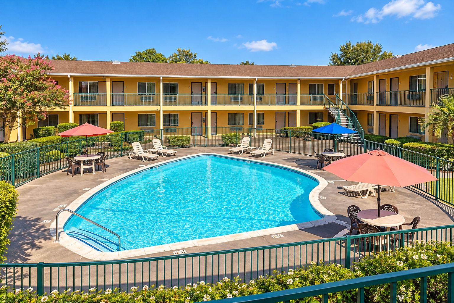 A hotel with a swimming pool, outdoor seating, and a multi-story building.