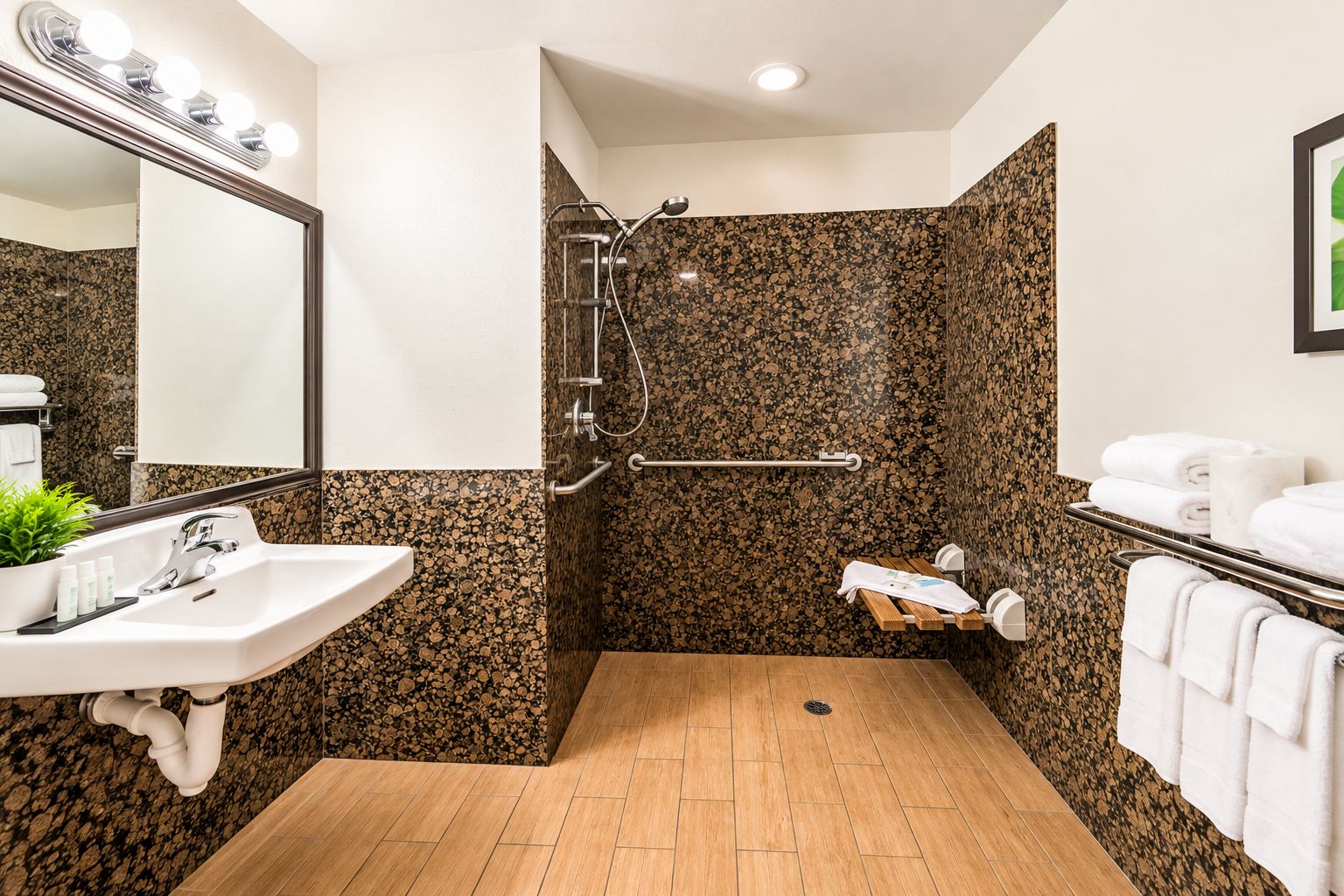 A bathroom with a sink, mirror, shower, and towel rack.
