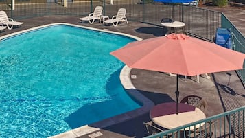 Una piscina al aire libre, sombrillas, sillones reclinables de piscina