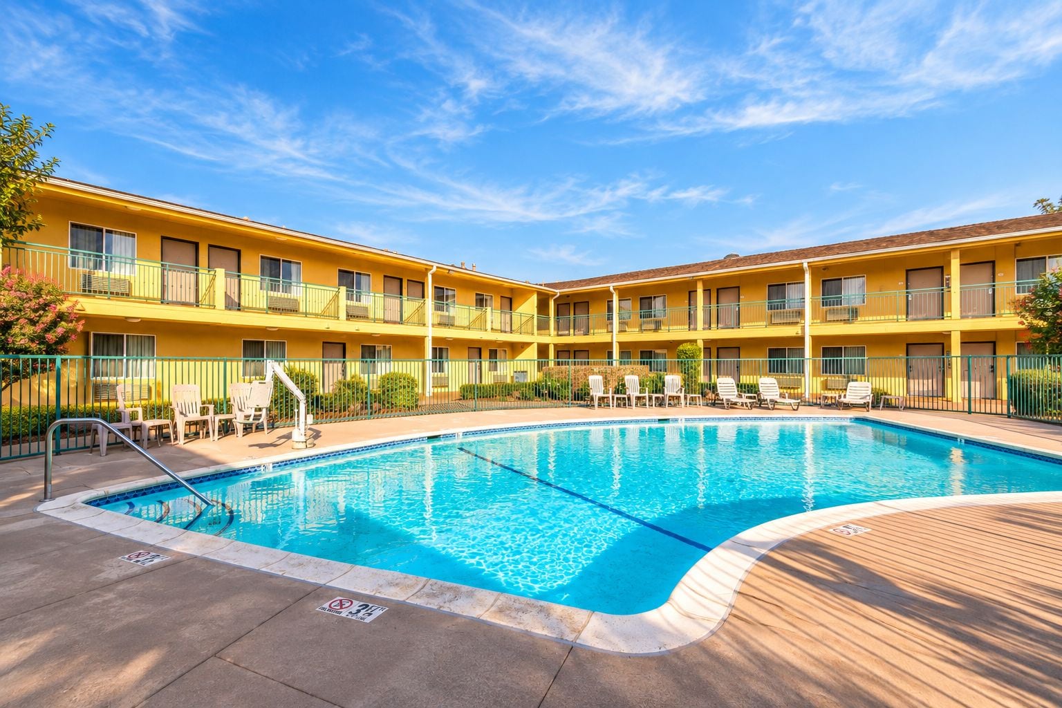 Um hotel com piscina, várias varandas e área de estar ao ar livre.