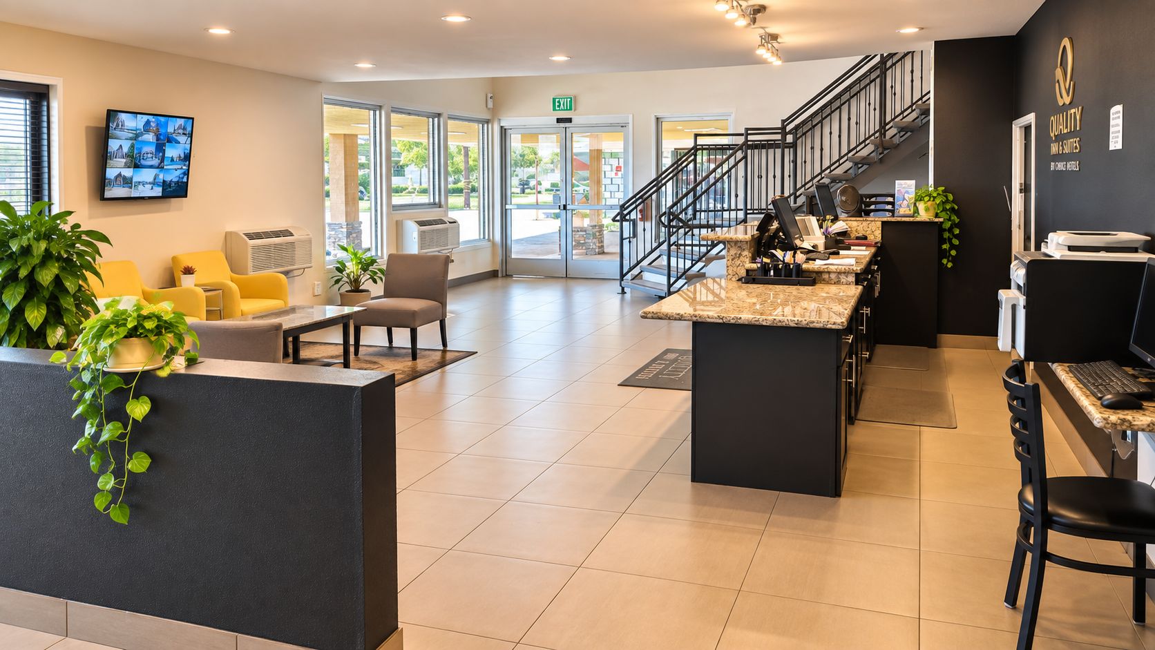 A hotel reception area with a counter, seating, and a staircase.