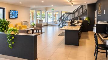 A hotel reception area with a counter, seating, and a staircase.