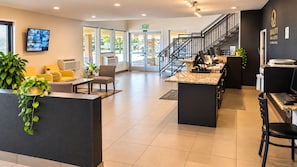 A hotel reception area with a counter, seating, and a staircase. - Quality Inn & Suites near Downtown Bakersfield (Bakersfield)