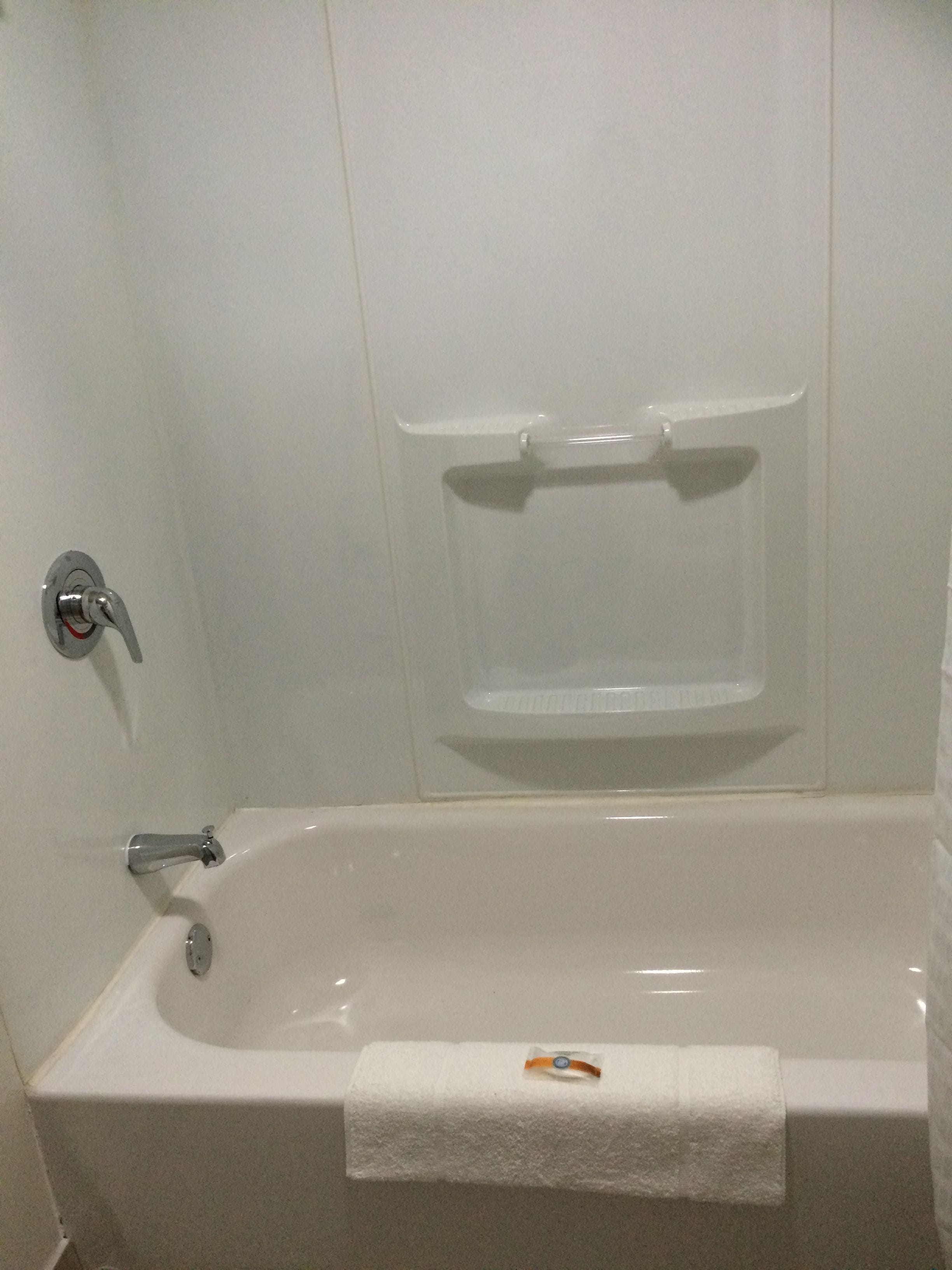 A white bathtub with a showerhead and a towel rack.