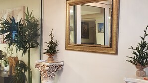 A room with a large mirror, two decorative columns, and potted plants.