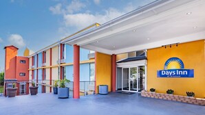A Days Inn by Wyndham with a modern facade, a covered entrance, and a clear sky.