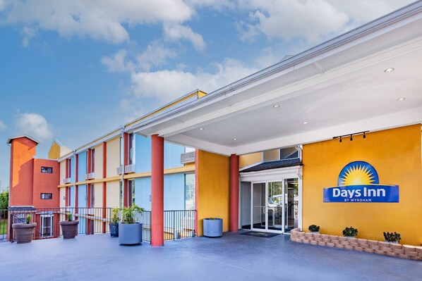 Welcome to Days Inn, featuring a modern exterior with a covered outdoor area and potted plants.