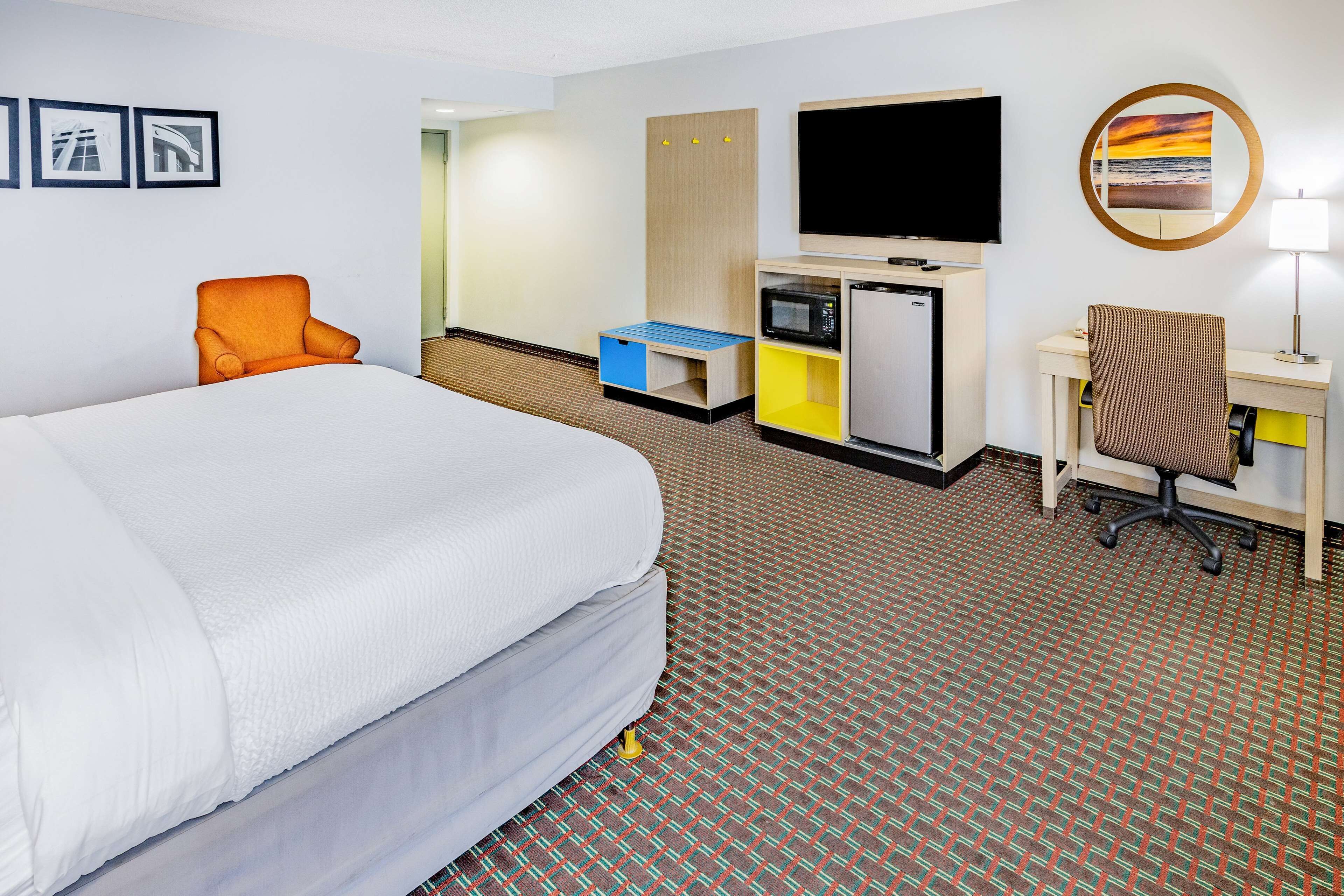 A hotel room with a large bed, a desk with a computer, a TV, and a chair.