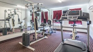 A gym with cardio machines, weightlifting equipment, and a mirrored wall.