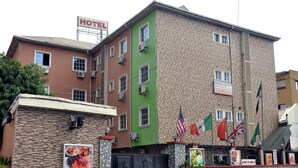 A multi-story hotel building with a prominent 'HOTEL' sign, multiple flags, and a sign for 'DEFINITE DESTINY HOTEL LTD.' - Definite Destiny Hotel (Lagos)