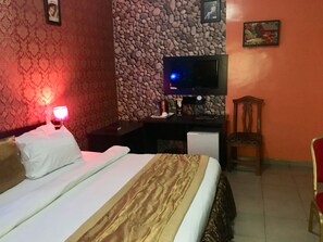 Una habitación de hotel con una cama, un escritorio con televisor, una silla y una pared con diseño de piedra.