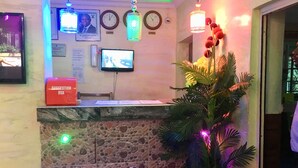 A reception area with a stone wall, a suggestion box, a clock, and a television. - Definite Destiny Hotel (Lagos)