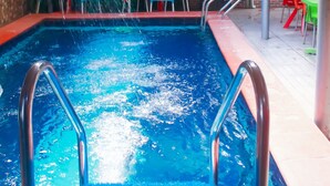 A swimming pool with a water feature, surrounded by outdoor seating and a staircase. - Definite Destiny Hotel (Lagos)