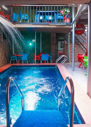 A swimming pool with a water feature, surrounded by outdoor seating and a staircase. - Definite Destiny Hotel (Lagos)