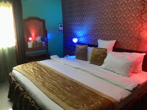 Una habitación de hotel con cama, mesita de noche, espejo y una lámpara de pared.