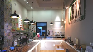 A café with a counter, seating area, and a wall with a menu. - Al Torrione (Reggio Calabria)