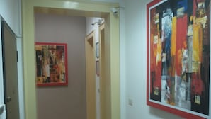 A hallway with a red carpet leading to a room. There are two framed artworks on the walls. - Al Torrione (Reggio Calabria)