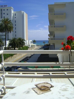A balcony with a view of a coastal cityscape, including a hotel named 'Don Juan'. - Hostal Saturno (Sant Llorenc des Cardassar)