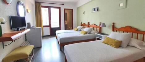 A hotel room with two beds, a TV, a desk, and a bathroom visible through an open door.