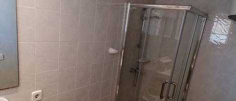 Een badkamer met een douchecabine, een wastafel, een toiletbrons en een toilet.