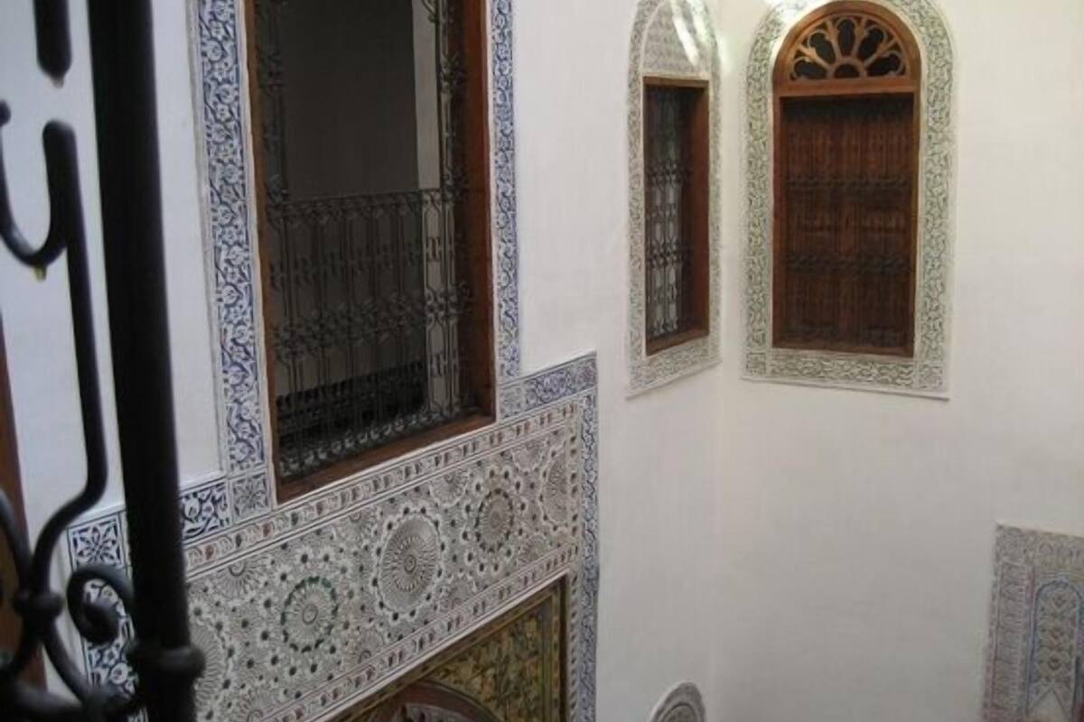 A room with ornate white walls, a patterned floor, and a wooden door.