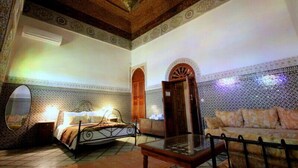 Quarto marroquino tradicional com cama, sofá, mesa e espelho.