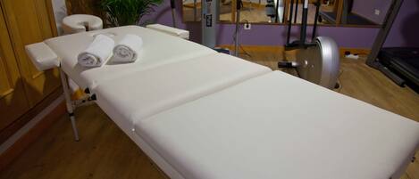 Een medische behandelkamer met een behandelbed, een massagetafel en fitnessapparatuur.