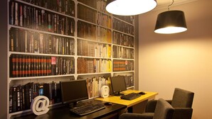 Una oficina en casa con dos escritorios, cada uno con un ordenador y teclado, y una amplia estantería llena de libros.