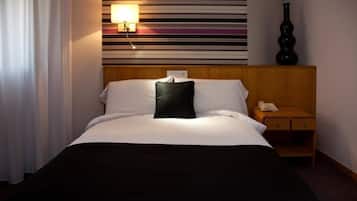 Une chambre d’hôtel avec un lit, une table de chevet, une lampe et un vase.