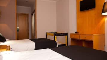 Habitació d'hotel amb dos llits, un escriptori de fusta, una televisió i una làmpada.