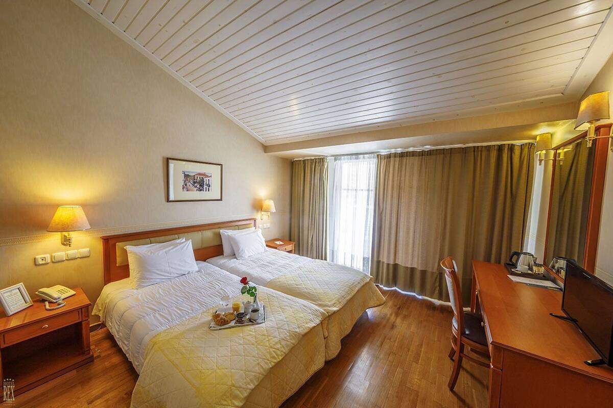 A hotel room with two beds, a desk, a chair, a phone, and a framed picture on the wall.