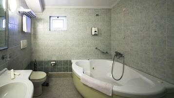 A bathroom with a bathtub, toilet, sink, and a small window.